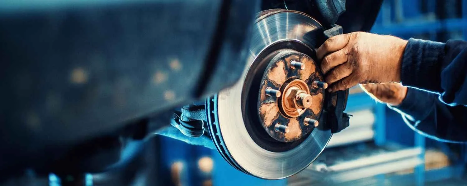 Technician examining a brake assembly with the wheel removed