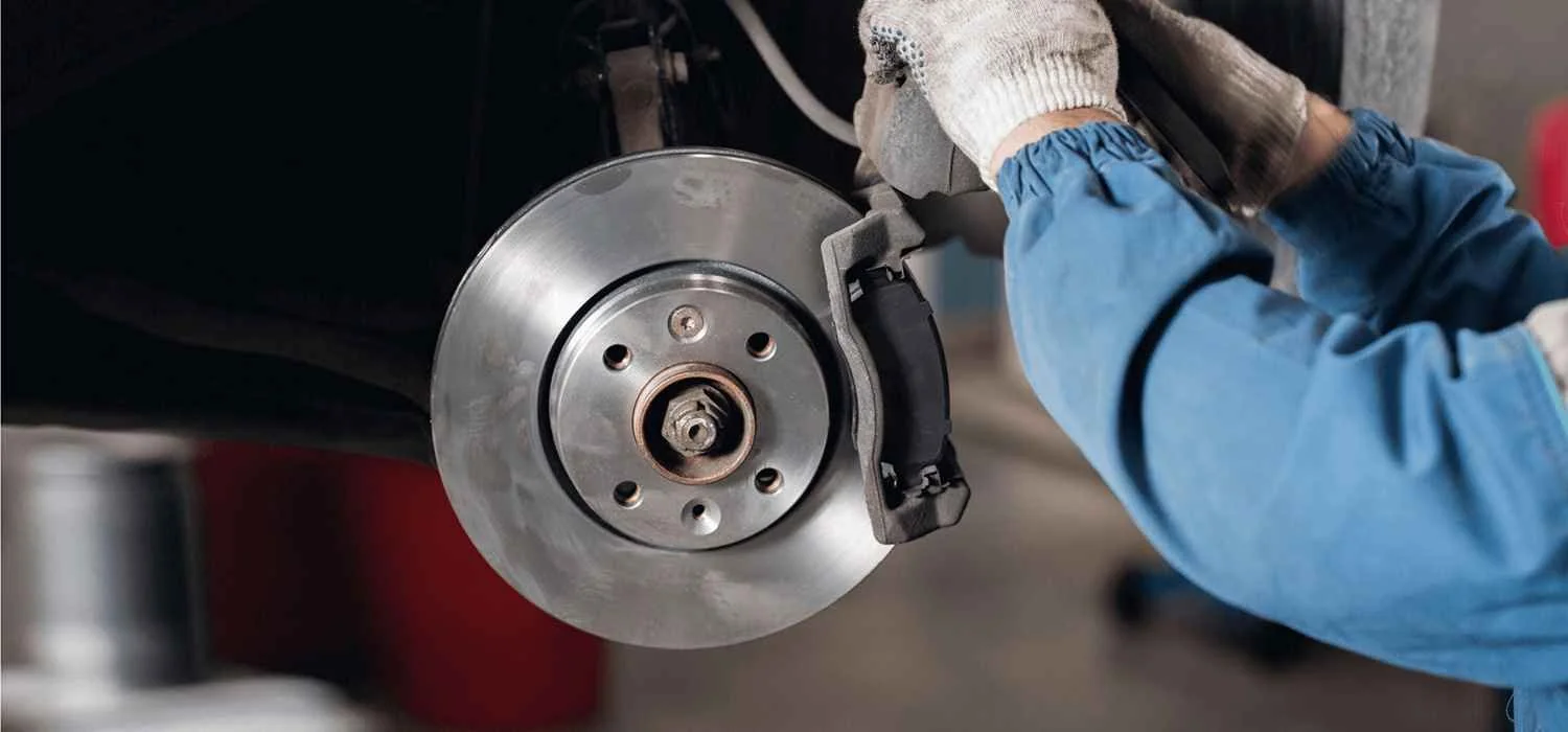 Technician working beside a brake disc during a brake service