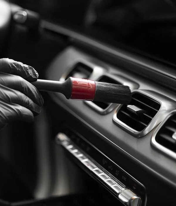 Soft detailing brush cleaning a dashboard air vent