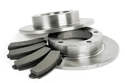 Brake pads placed beside two brake discs on a white background