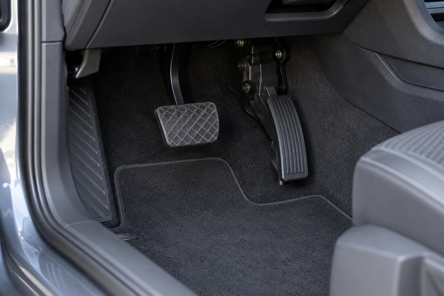 Generic accelerator and brake pedals viewed in a parked left-hand-drive car